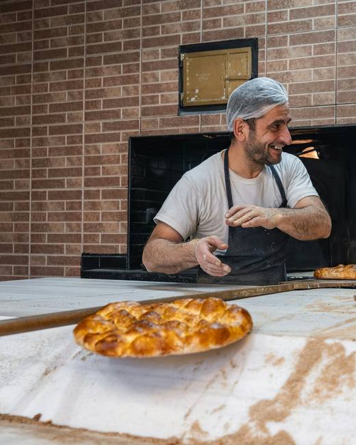 Theo, the founder, smiling as he pulls bakes from the brick oven