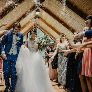 Priya and Sam, confetti in the Great Barn