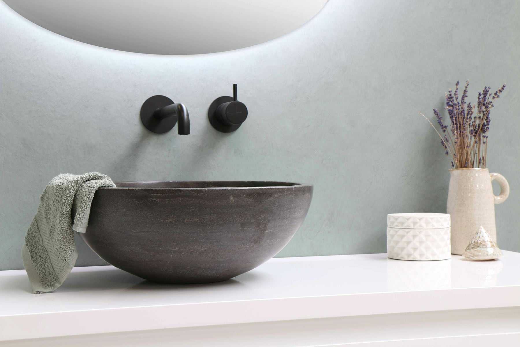 A stone bowl basin with black wall-mounted taps