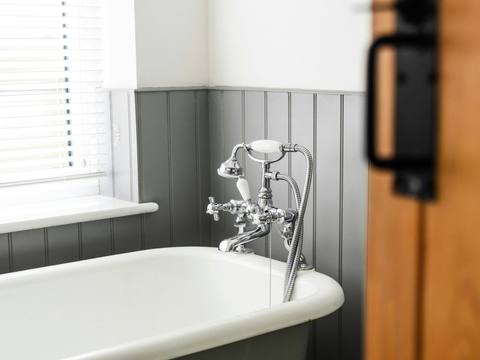 A roll-top bath in a panelled bathroom