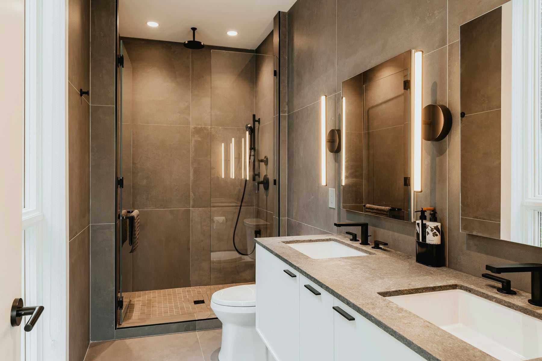 A walk-in shower with a glass screen and double basins