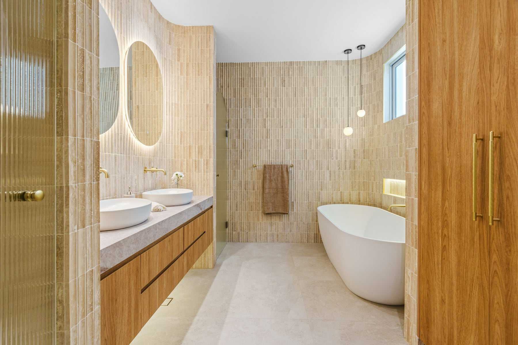 A warm-toned bathroom with oak cabinets and a freestanding bath