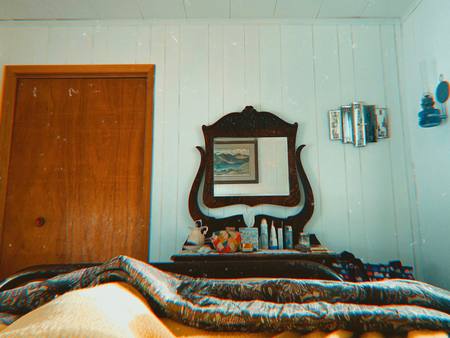 A bedroom with an antique dresser and a patchwork bedspread