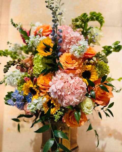 A bright bouquet of sunflowers, hydrangea and orange roses