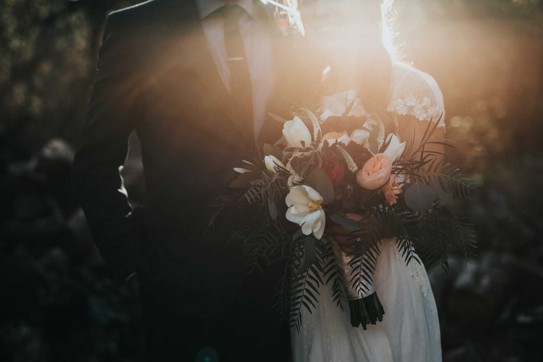 A bridal bouquet held against a dark background in soft light