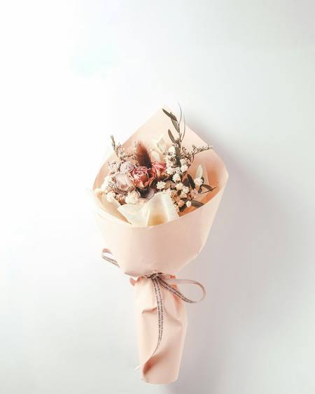 A small dried flower posy in peach paper