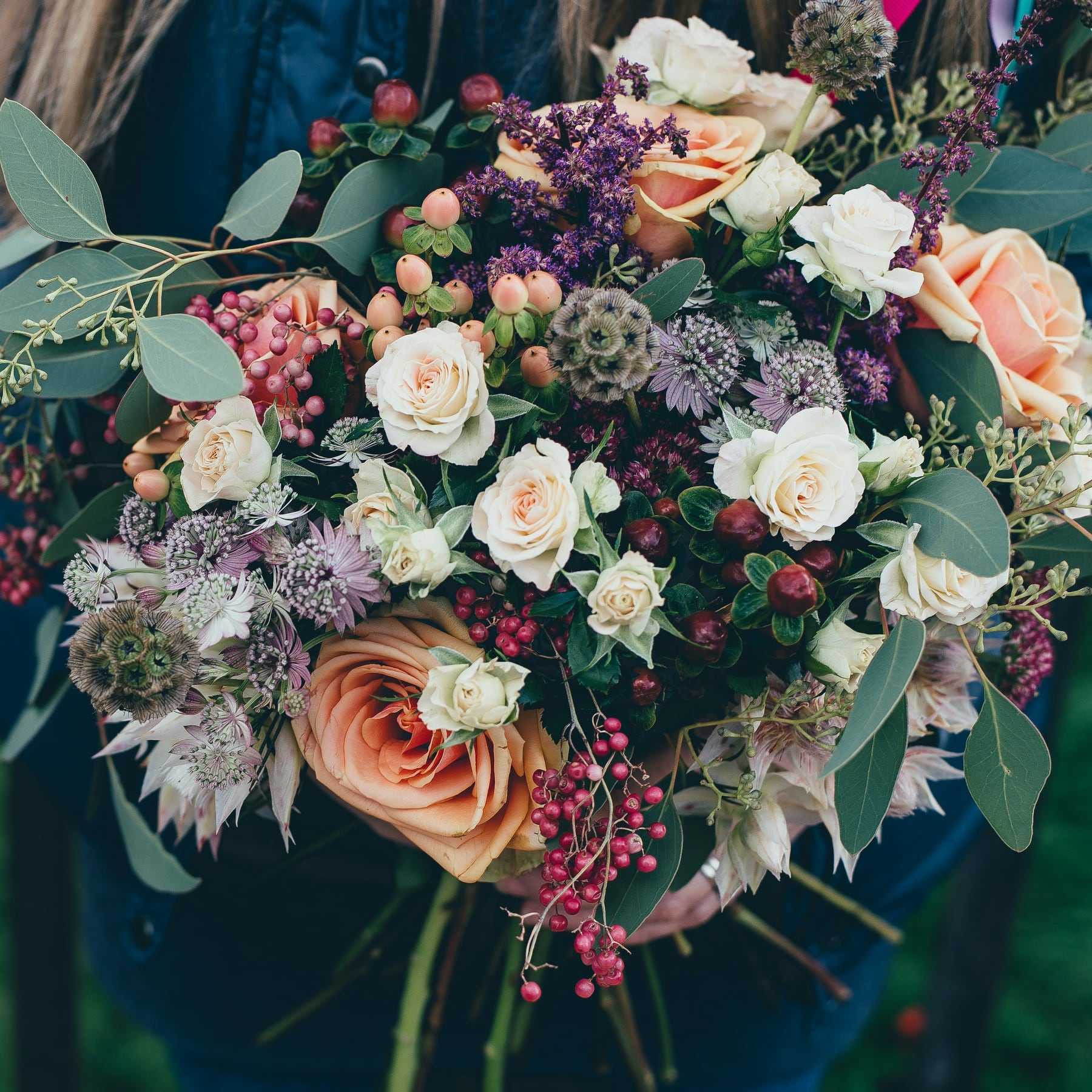 A wild, loose bouquet of roses, berries and thistles