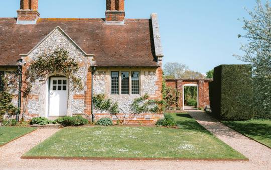 A brick and flint cottage with a neat front garden and a path to the door
