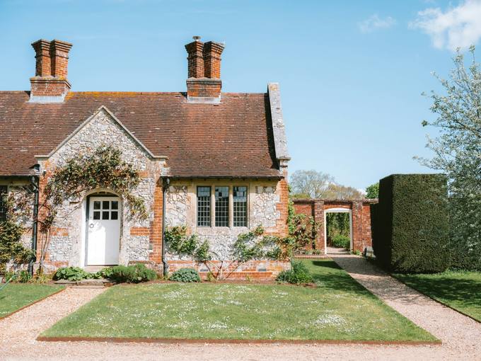 The brick and flint front of the cottage with a lawn and path