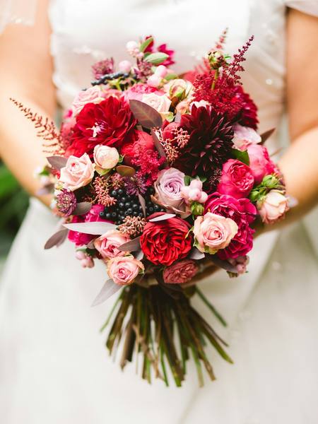 A bride holding a bouquet of red and pink roses