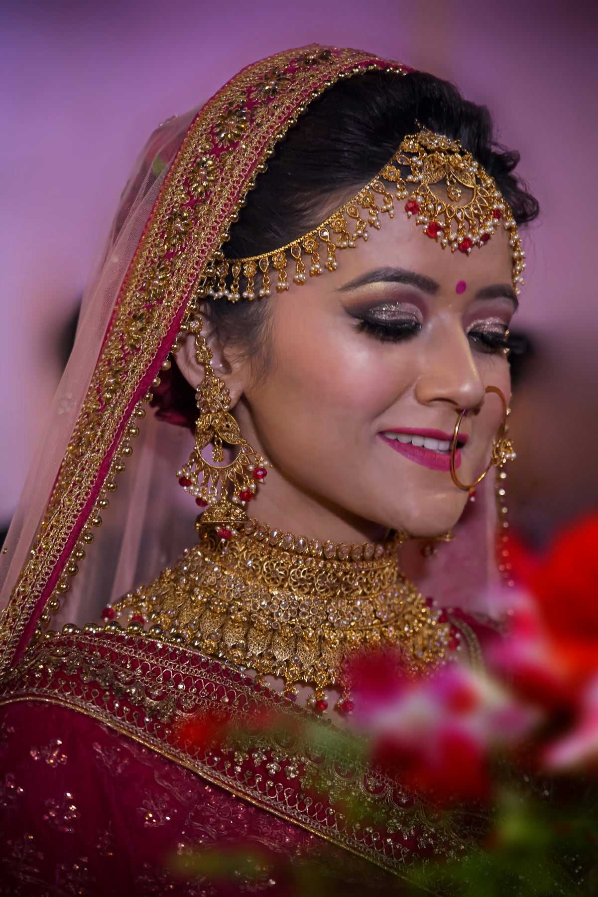 A bride in traditional gold jewellery smiling softly