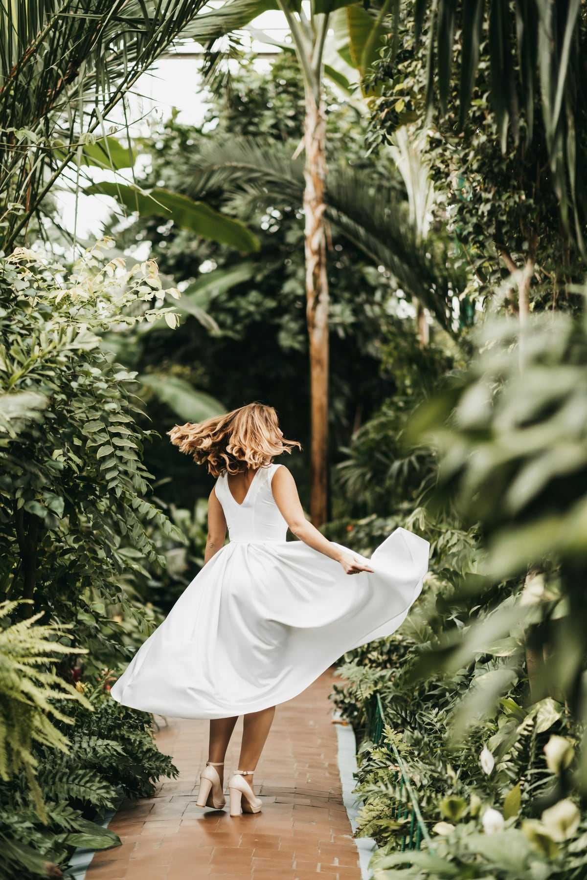 A bride twirling her dress in a leafy garden