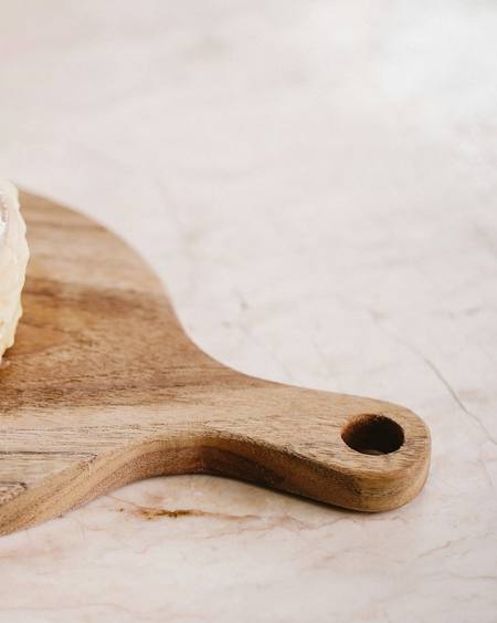 A glazed cinnamon and cardamom bun on a wooden board