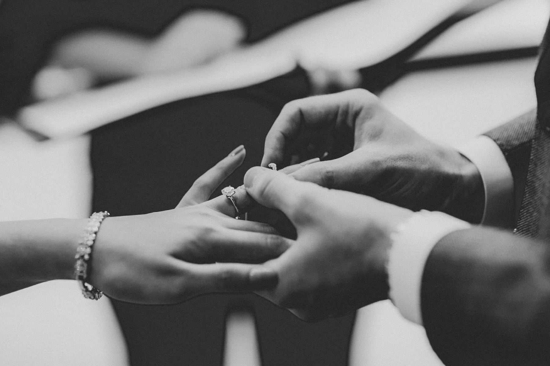 Black and white close-up of a ring being placed on a finger