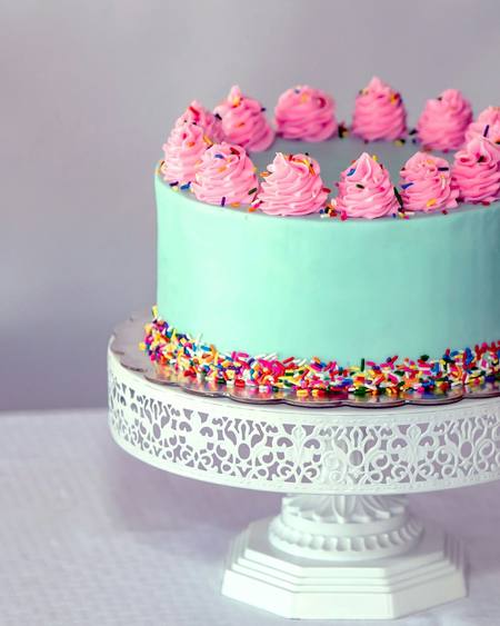 A mint green cake with pink buttercream swirls and sprinkles