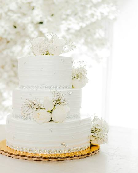 A three tier white wedding cake with fresh flowers