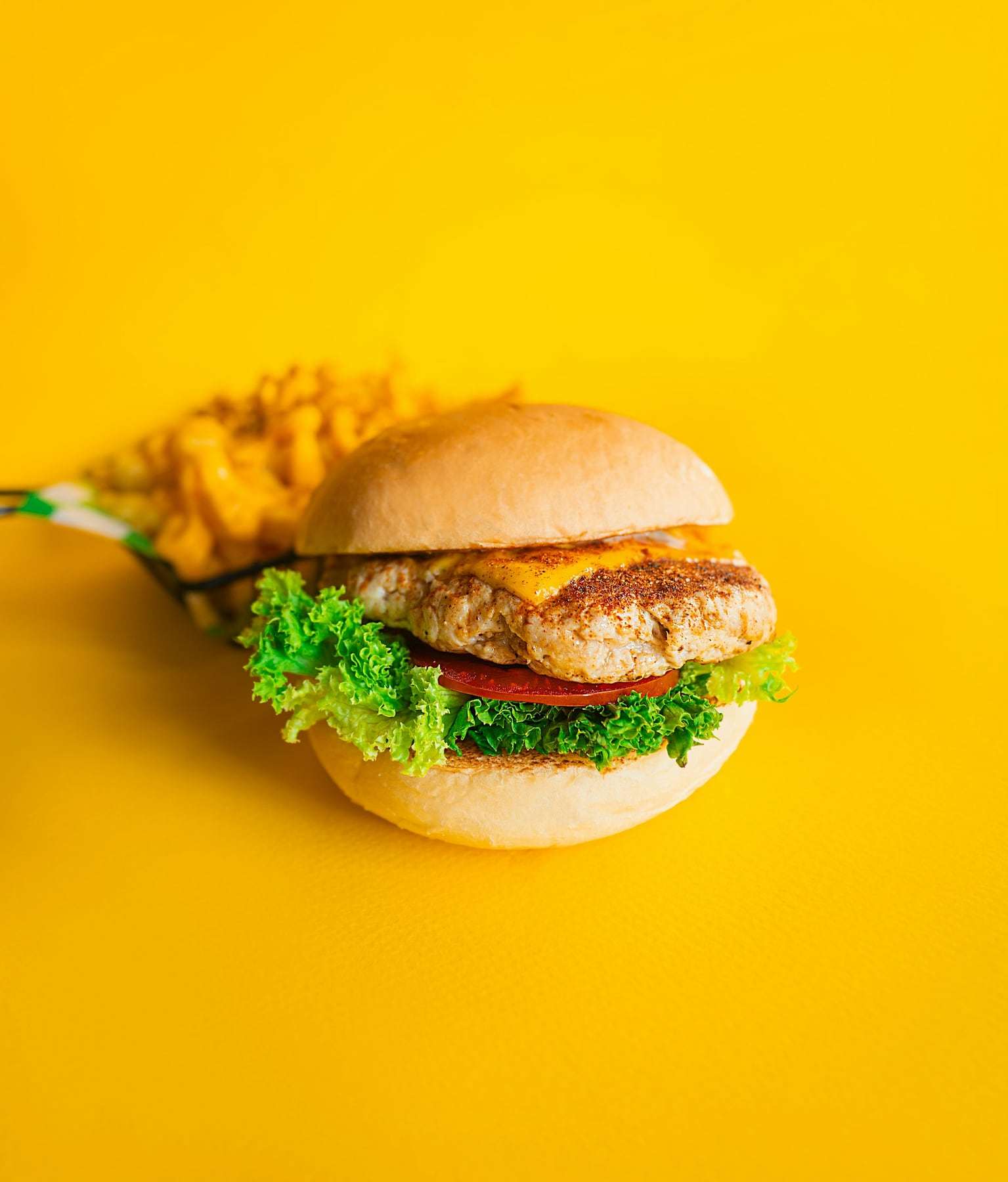 A crispy chicken burger with lettuce on a yellow background