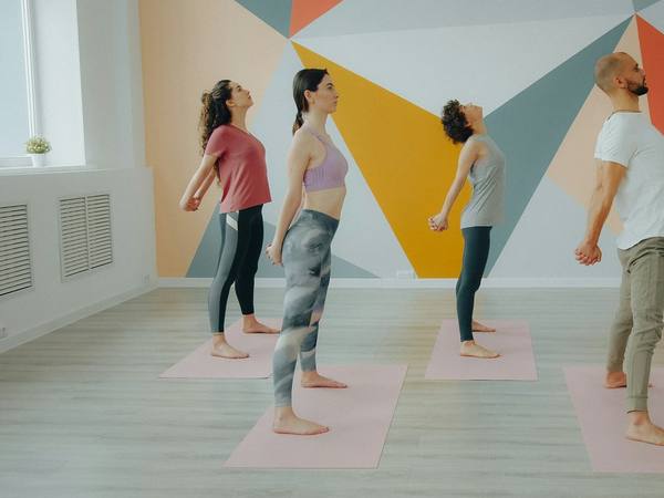 A class flowing through a standing pose in front of a painted wall