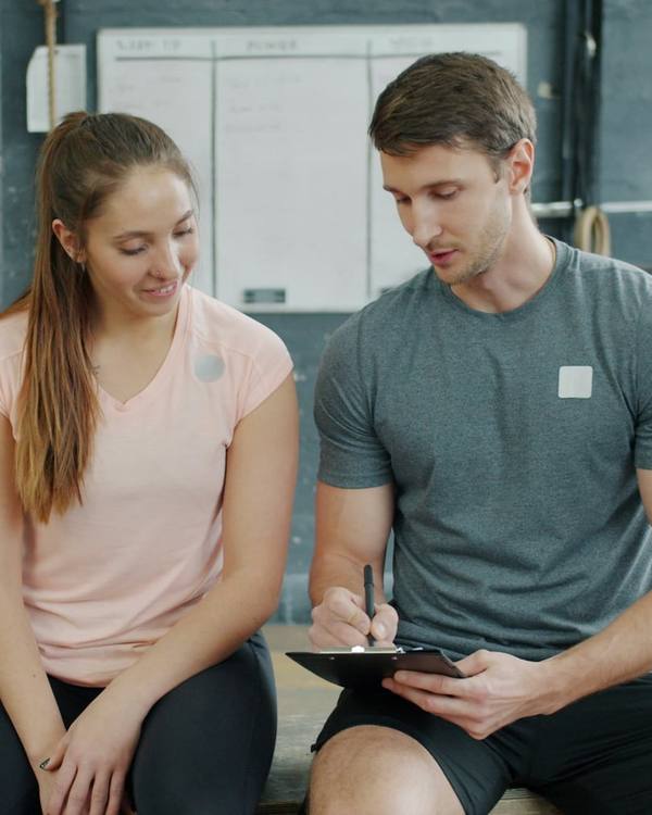 A coach going through goals with a new client on a gym bench