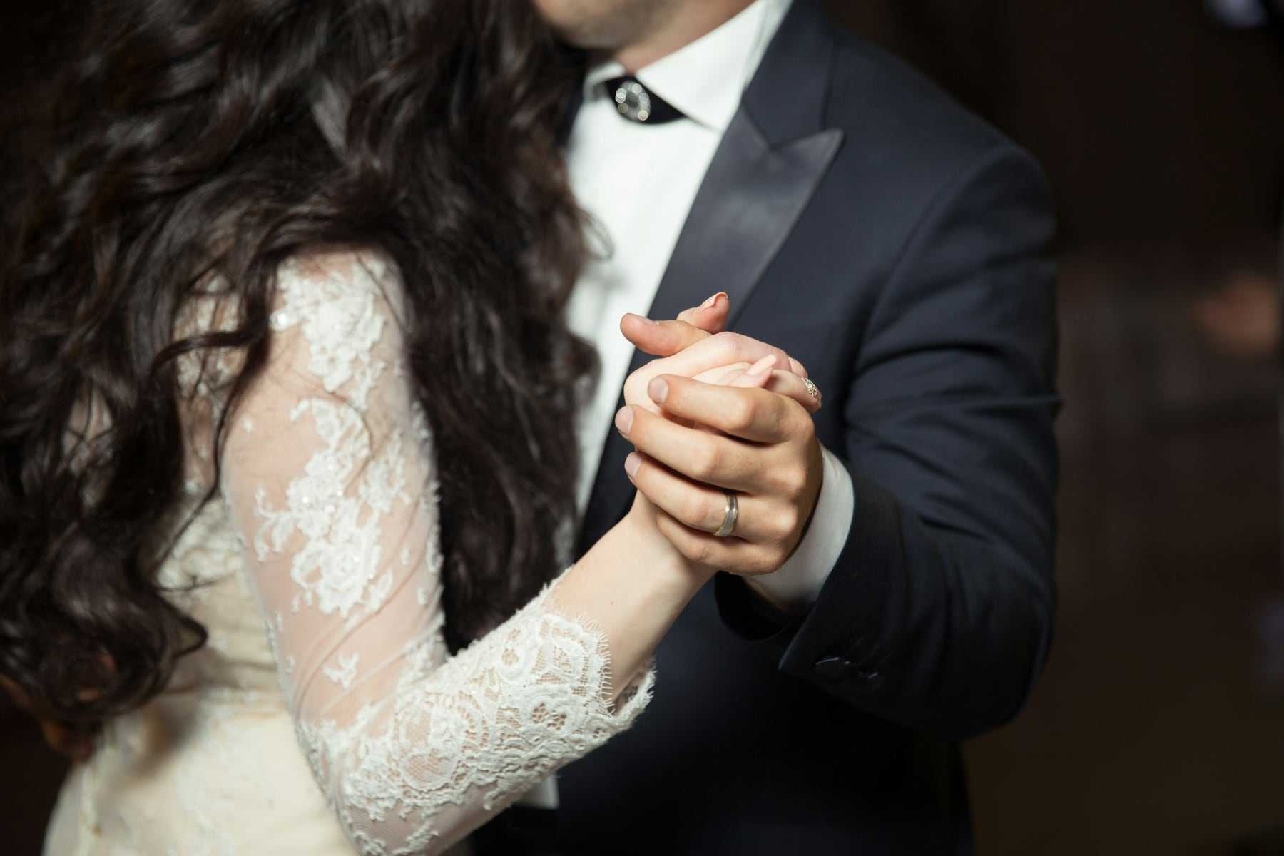A close-up of the couple holding hands during their first dance