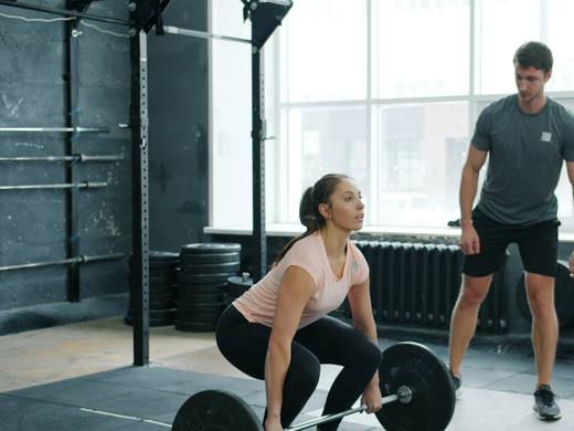 A coach watching a client set up for a deadlift