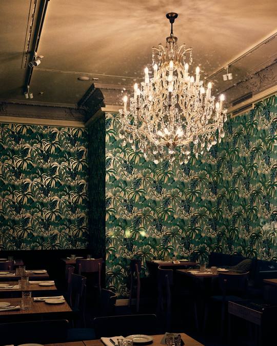 The restaurant with green botanical wallpaper and a crystal chandelier