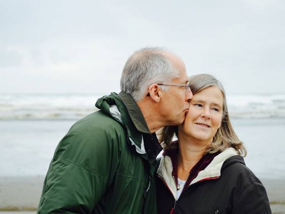 An older couple sharing a hug by the sea