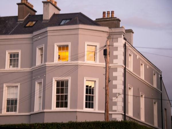 A pink-rendered Georgian villa with bay windows at dusk