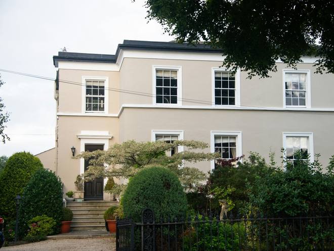 A cream Regency townhouse with tall sash windows behind a green front garden