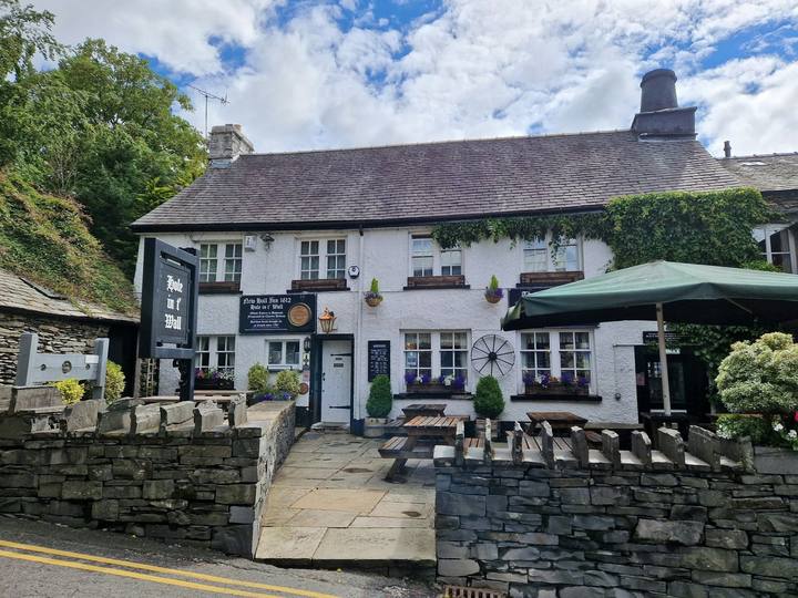 The whitewashed front of the inn with drystone walls and a garden umbrella
