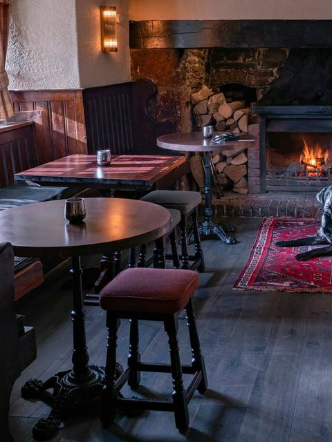 A dog asleep on a rug in front of the open fire in the bar