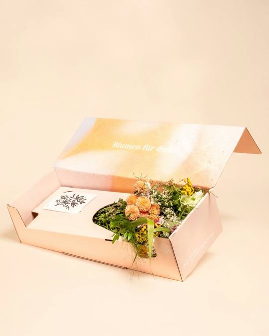 A flower box with greenery and a handwritten card inside