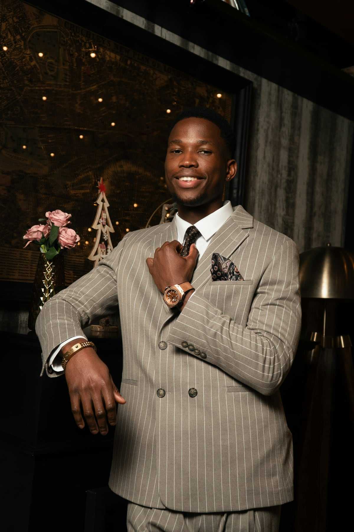 A smiling groom in a checked suit adjusting his jacket