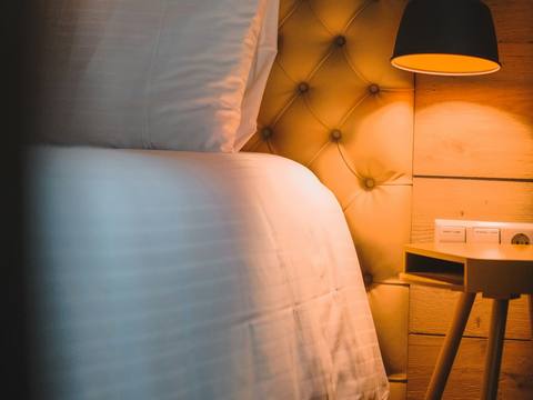 A tufted velvet headboard lit by a reading lamp