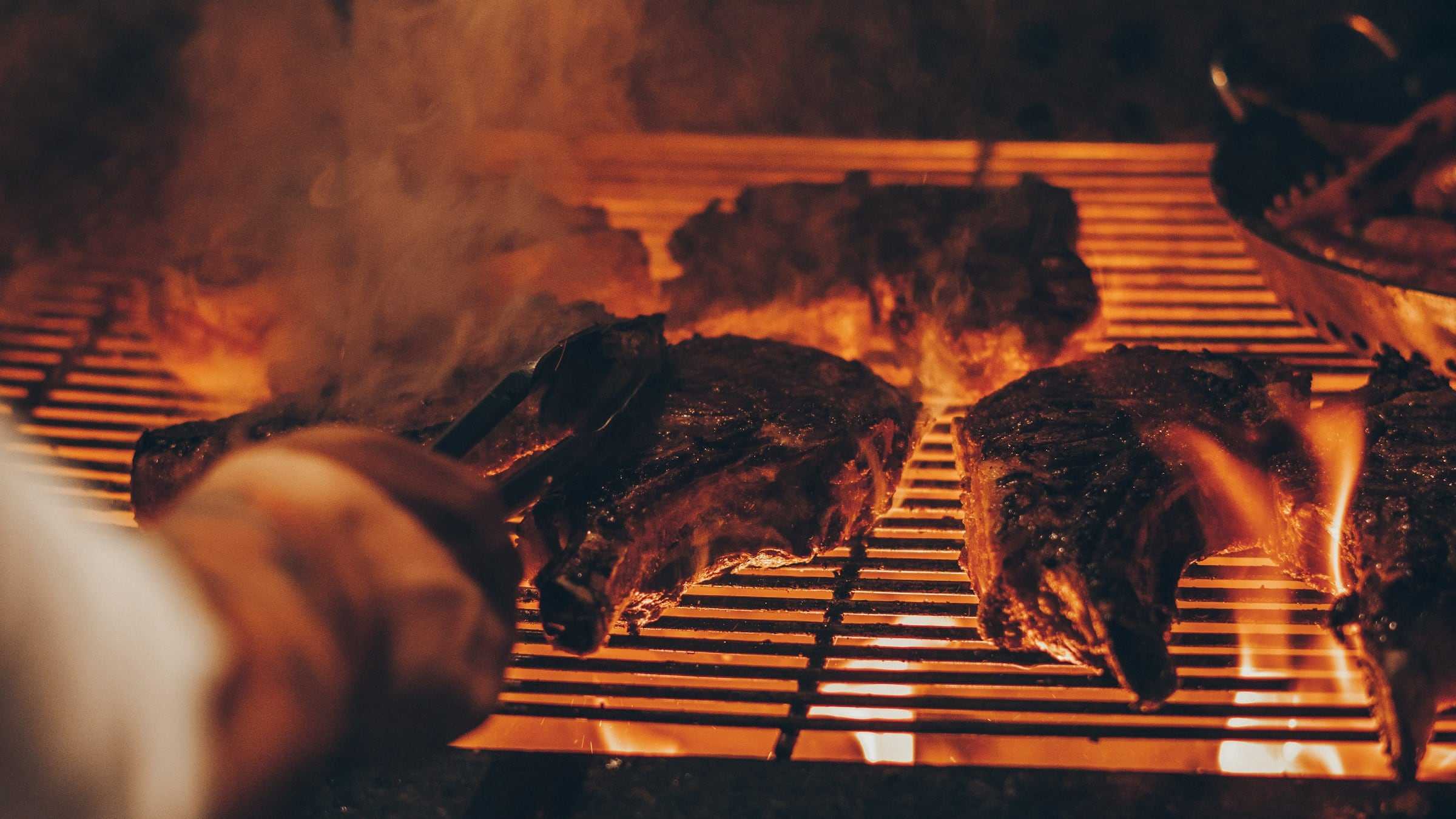 Steaks cooking over open flames