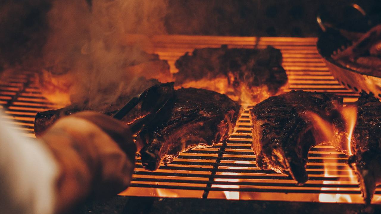 Steaks cooking over open flames on the hearth