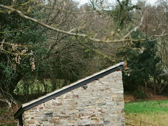A small stone building with a wooden hot tub outside