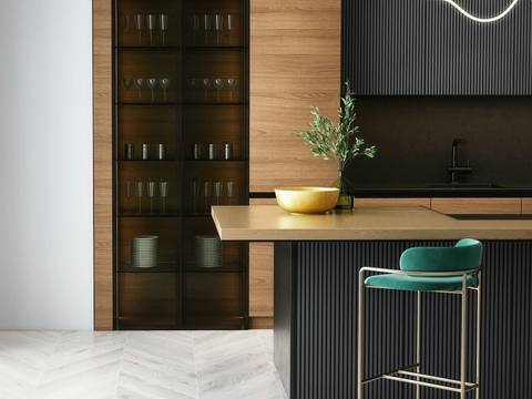 A kitchen with dark cabinets, oak worktops and green stools