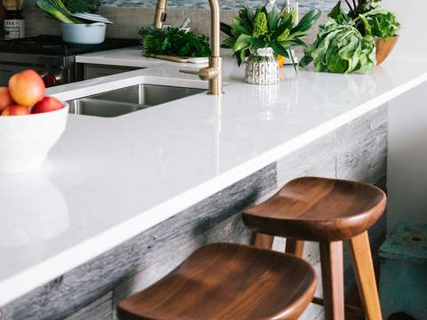 A marble kitchen island with brass taps and wooden stools