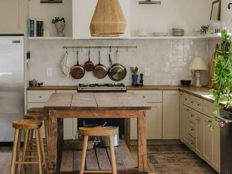 A rustic kitchen with a wooden island and hanging pans