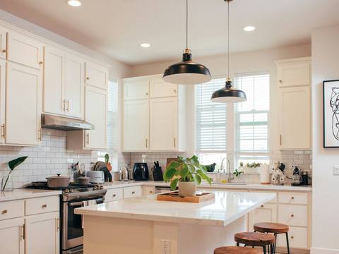 A white kitchen with an island and pendant lights