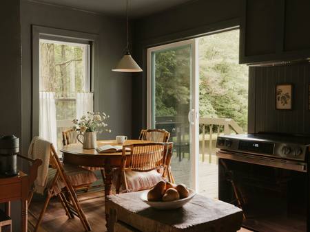 A dark green kitchen with a dining table by the garden doors