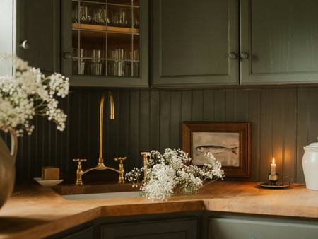 A green-painted kitchen with candles and a deep sink