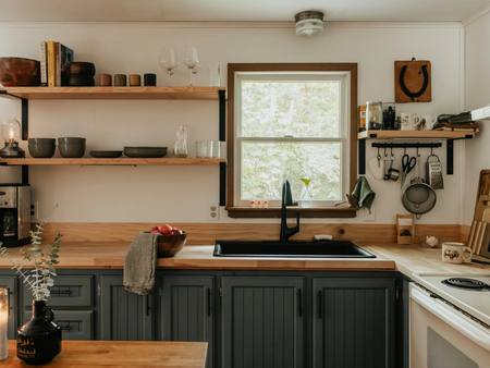 A cottage kitchen with open shelves and a window over the sink