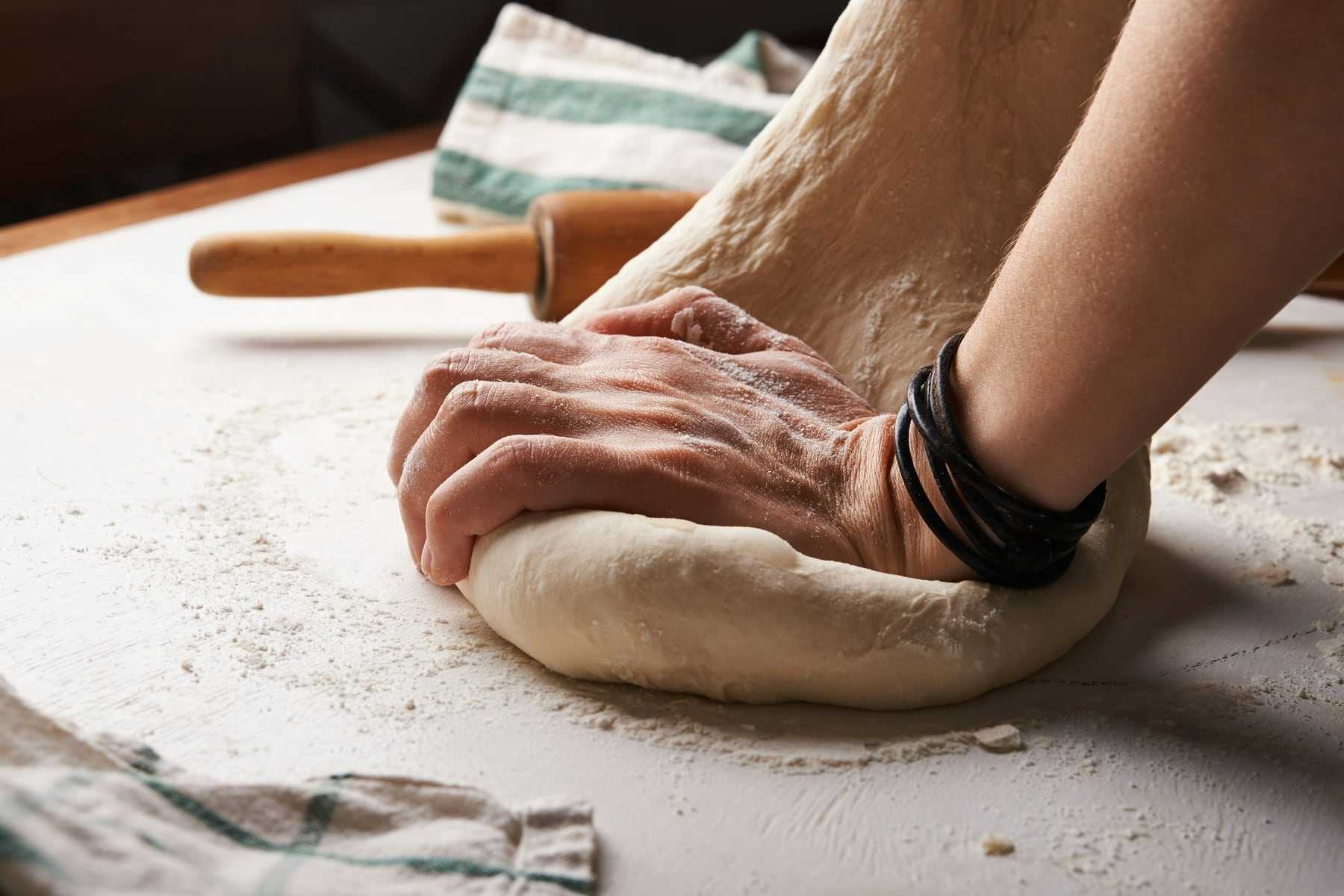 A baker kneading dough on a floured table