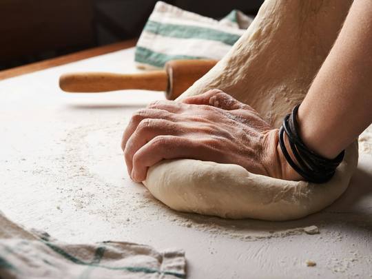 Hands kneading a ball of dough