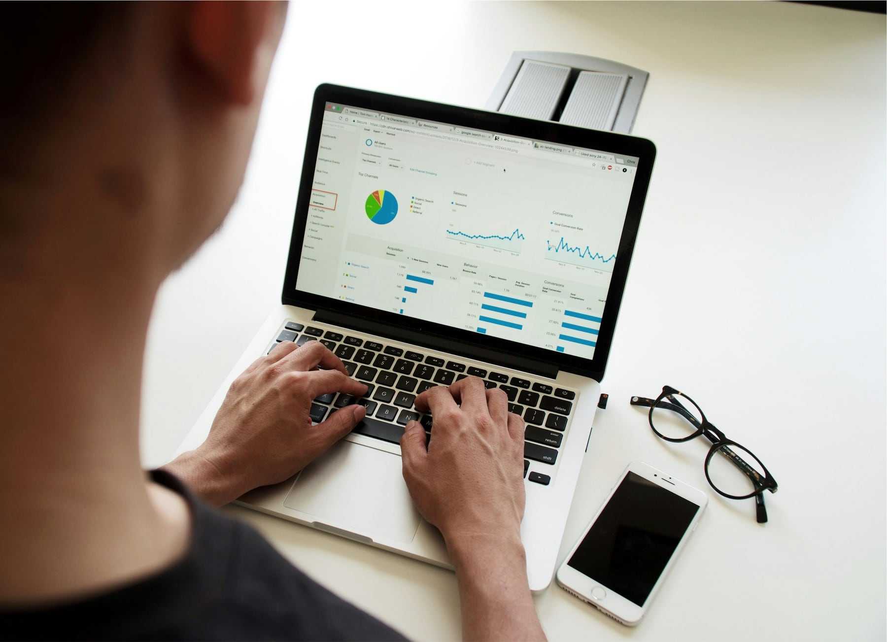 Hands typing on a laptop showing charts and figures