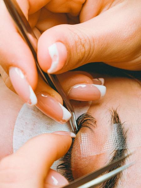 A technician applying lash extensions with tweezers