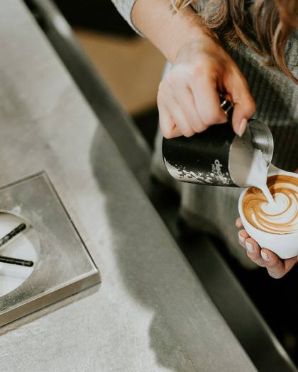 A barista pouring latte art into a cup