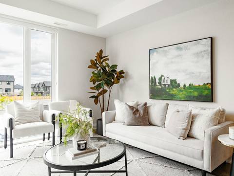A white living room with a large painting and plants